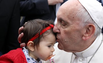 Pope Francis kisses the forehead of a young child during the welcome ceremonies at Monte Real Air Base in Leiria, Portugal, on May 12, 2017. Pope Francis is in visiting Fatima on May 12 and 13 on the 100th anniversary of the appearances of Mary. Photo: EPA