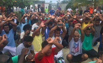 Refugees inside the Manus detention camp in Papua New Guinea gesture in defiance on the day of the camp's closure. The PNG government has warned it could use force to remove a group of asylum seekers who have refused to leave. Photo: AFP