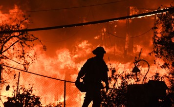 A firefighter is silhouetted by a burning home along Pacific Coast Highway during the Woolsey Fire in Malibu, California. Photo: AFP