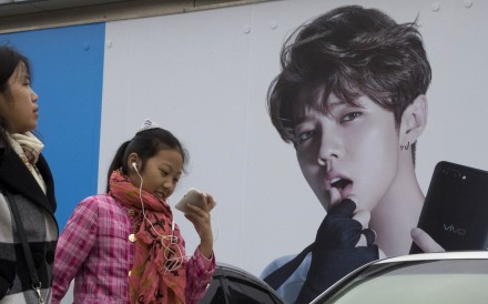 Chinese millennials walk past advertisement featuring teen idol Lu Han, also known as China's Justin Bieber in Beijing Photo: AP