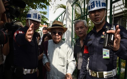 Thai academic and historian Sulak Sivaraksa is escorted by police from the Bangkok Military Court. Photo: AFP