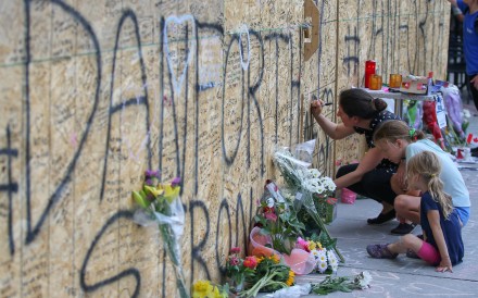 People write messages on construction boarding after a mass shooting on Danforth Avenue in Toronto. Photo: Reuters
