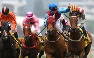 Sam Clipperton (blue and red silks) points to the grandstand after winning the Hong Kong Macau Trophy on Invincible Dragon. Photos: Kenneth Chan