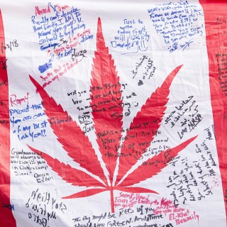 People hold up a Canadian flag with a marijuana logo on it outside a government cannabis store in Montreal. Photo: AP