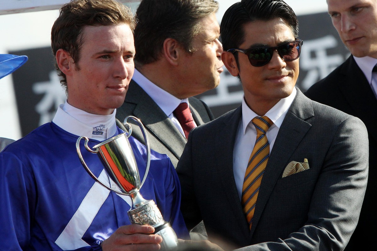 Aaron Kwok hands a trophy to jockey Ryan Plumb. Photo: David Wong