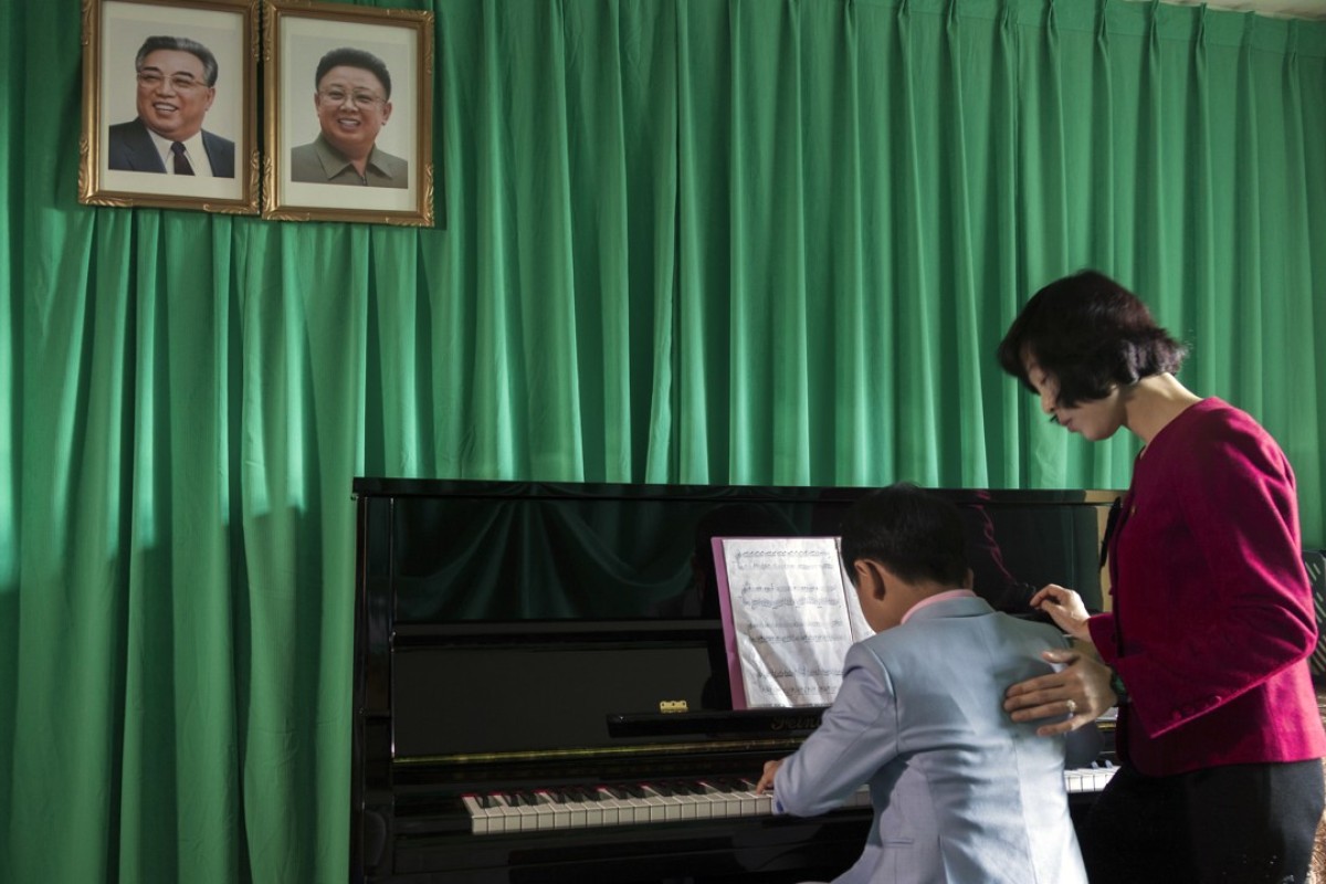 A piano lesson beneath the portraits of Kim Il-sung and Kim Jong-il at the Steelworks Kindergarten in Chongjin, North Hamgyong province. The school is famous for nurturing talented musicians and dancers. Visitors to the school are treated to an hour-long performance.